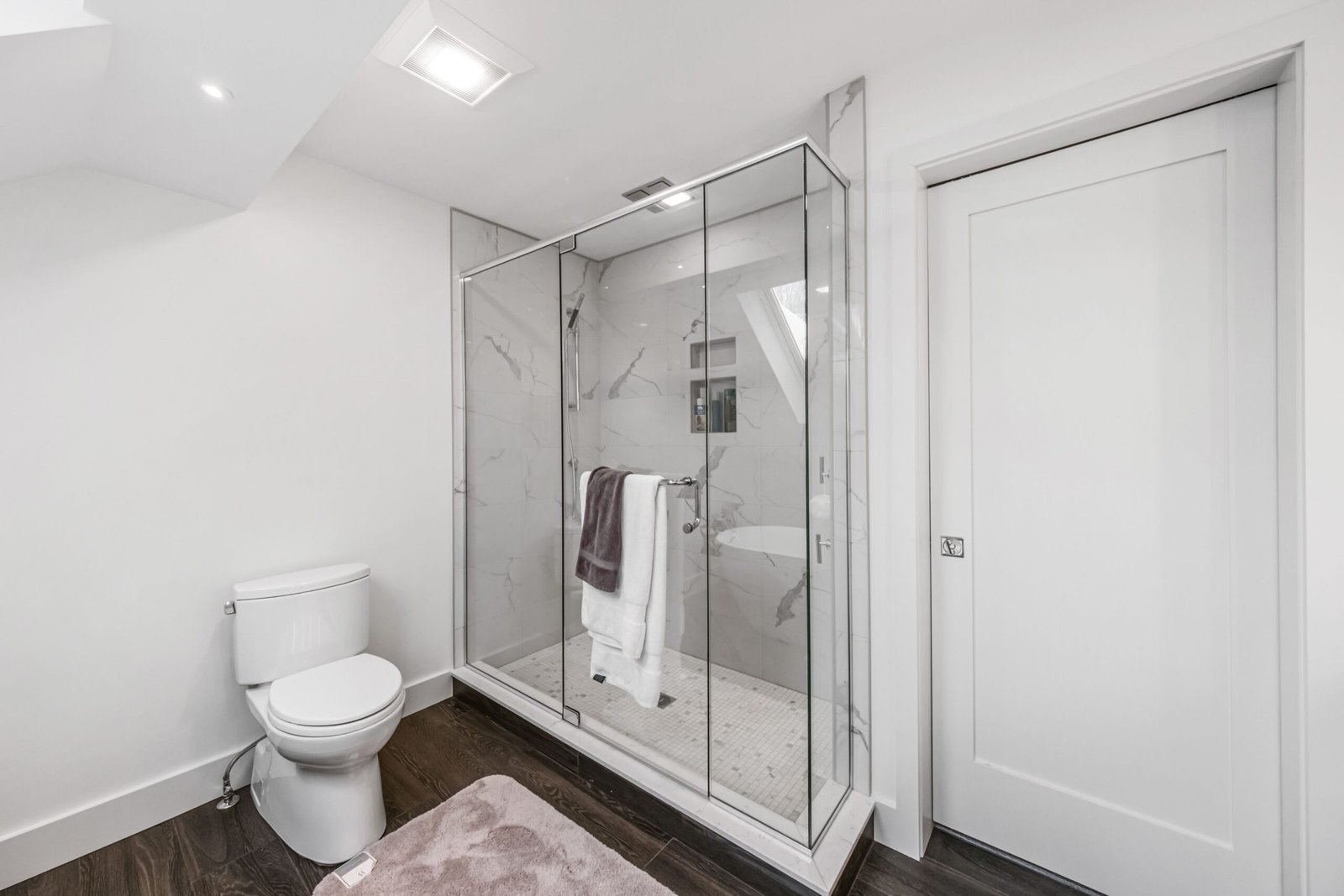 A white minimalist bathroom interior with glass partition
